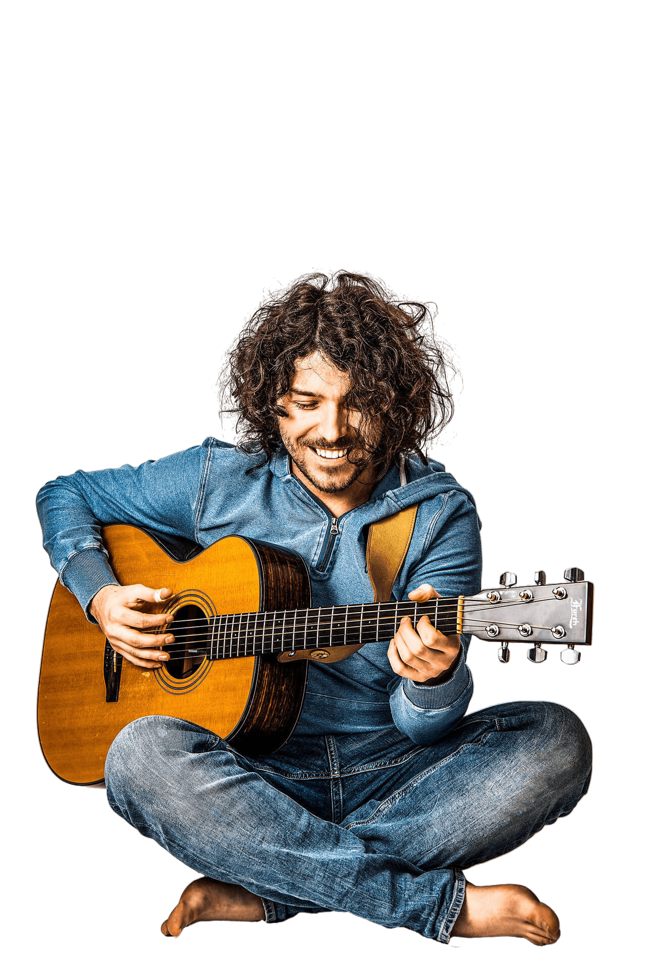 Michał Świąder siedzi boso na podłodze z gitarą akustyczną, ciepły uśmiech